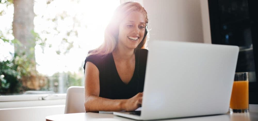 Woman with laptop at home preparing for exam with Swiss Exams Academy